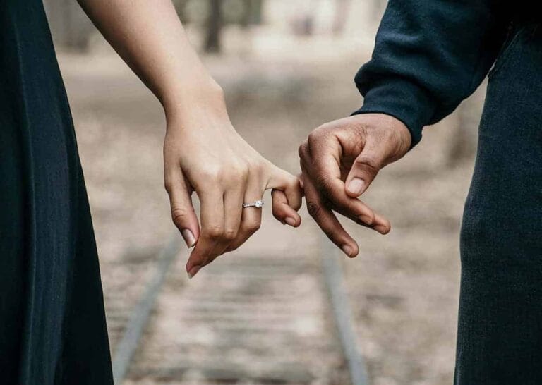 Holding hands of a couple at a park during the day.