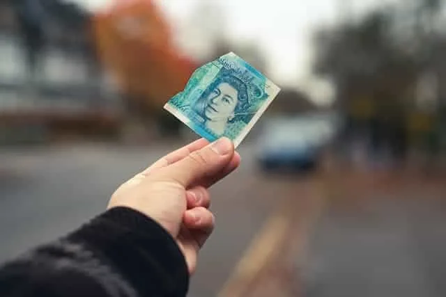 Banknote held in hand on a city street, showcasing financial management and investment opportunities.