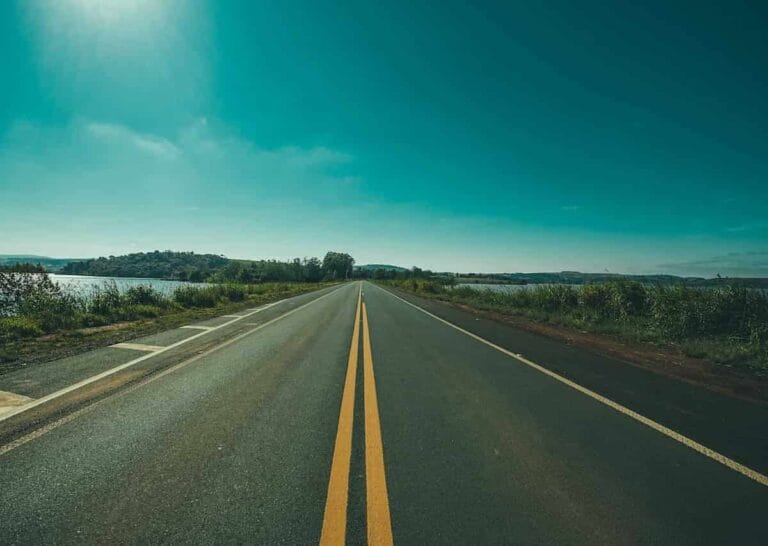 Open road by a lake under a clear blue sky, representing long-term investment and strategic planning.