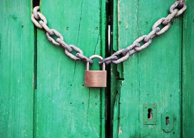 Secure green wooden door with metal chain and padlock for asset protection.