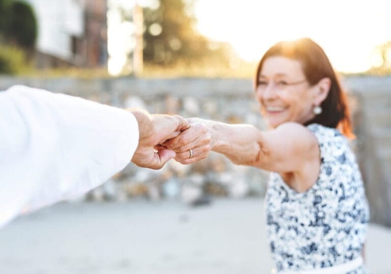 Warm embrace between senior and younger woman outdoors in sunlight.