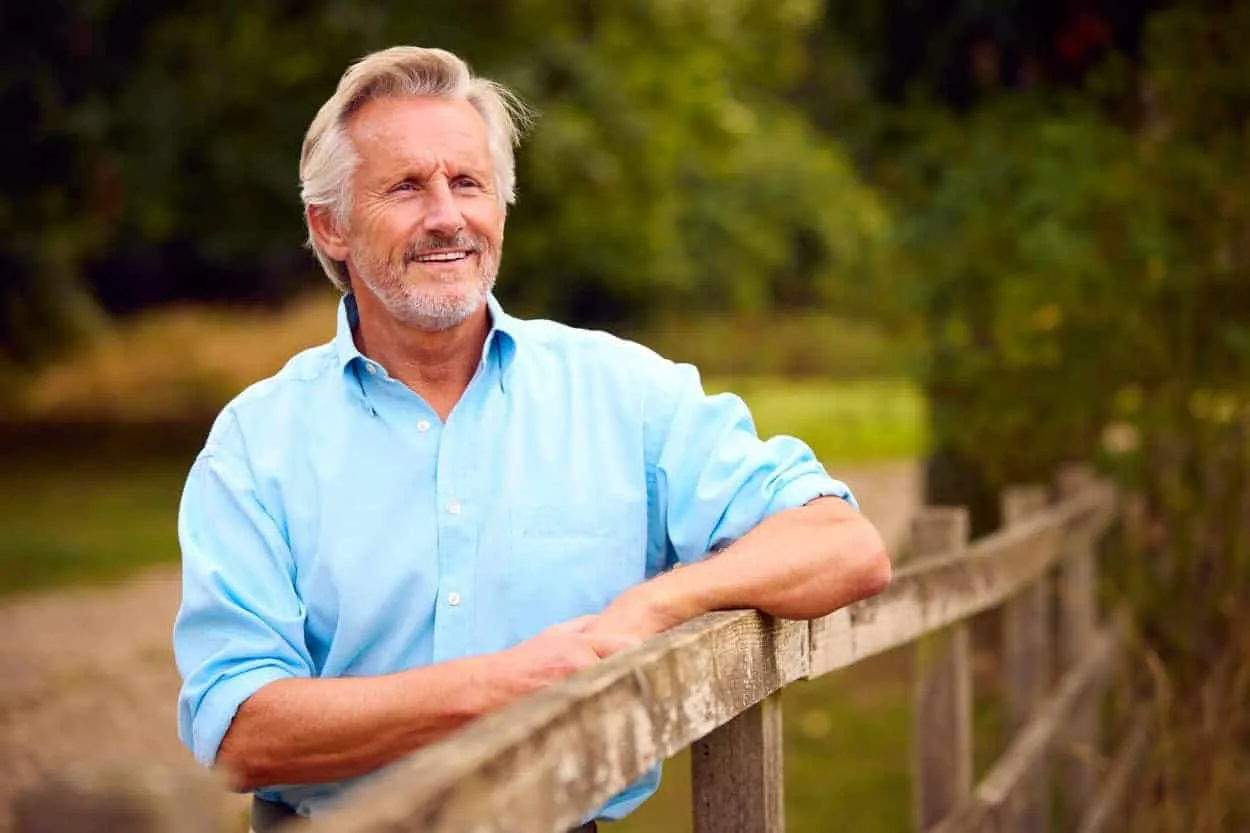 Senior man enjoying outdoor view in a rural setting, symbolising stability and strategic planning for asset management.